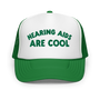 Green and white 'Hearing Aids Are Cool' embroidered trucker hat with mesh back.